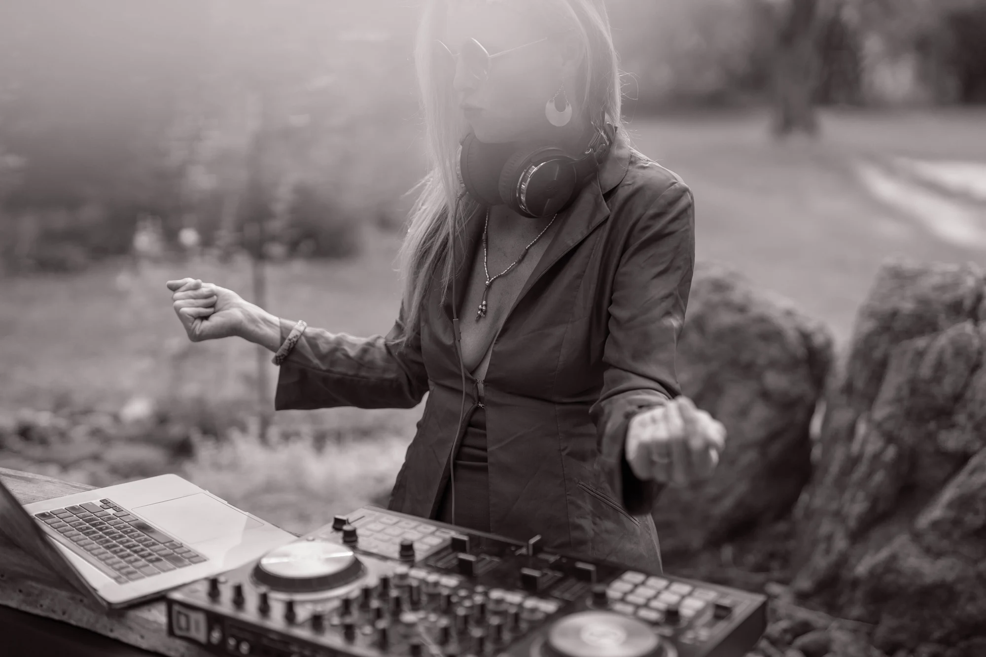 Black-and-white photograph of Asha moving to the music behind her DJ decks, washed in soft sunlight