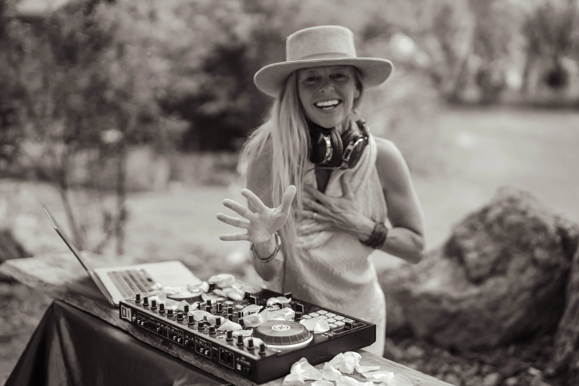 Asha smiling with one hand over her heart behind the DJ decks